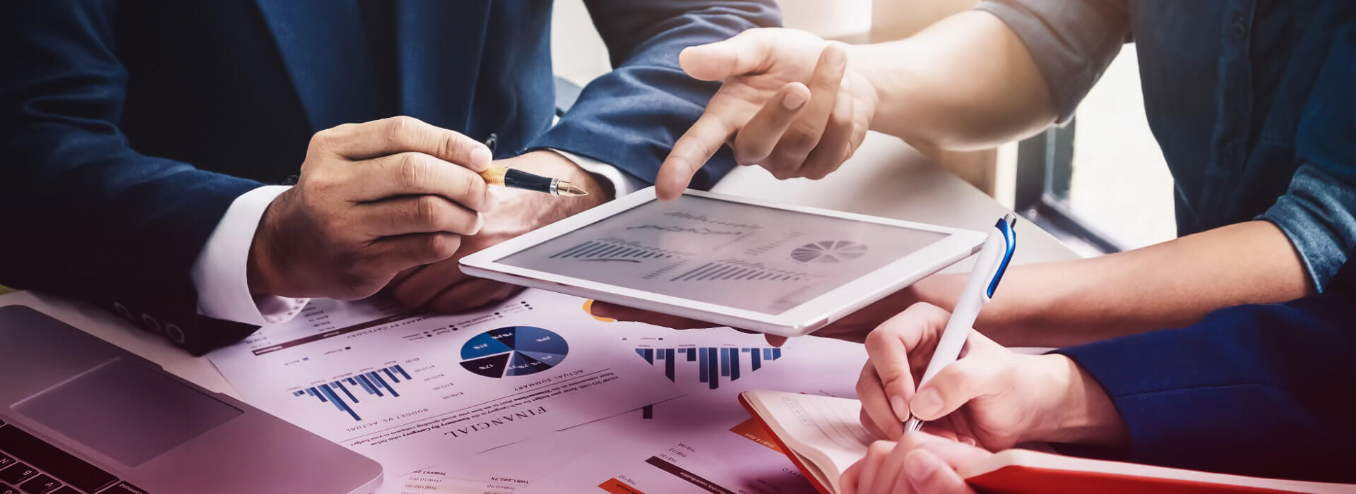 image of printouts, tablet and laptop during a meeting