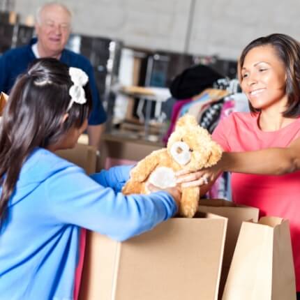 girl pulling out stuffed teddy bear from box